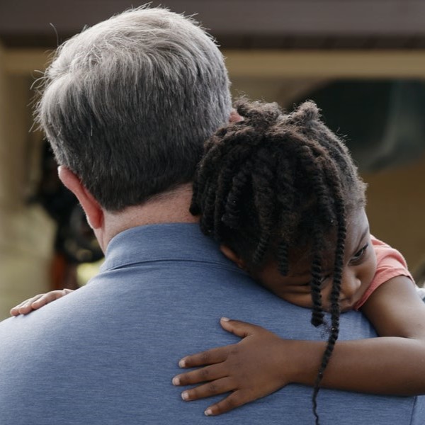 A man carries a little girl on his shoulder